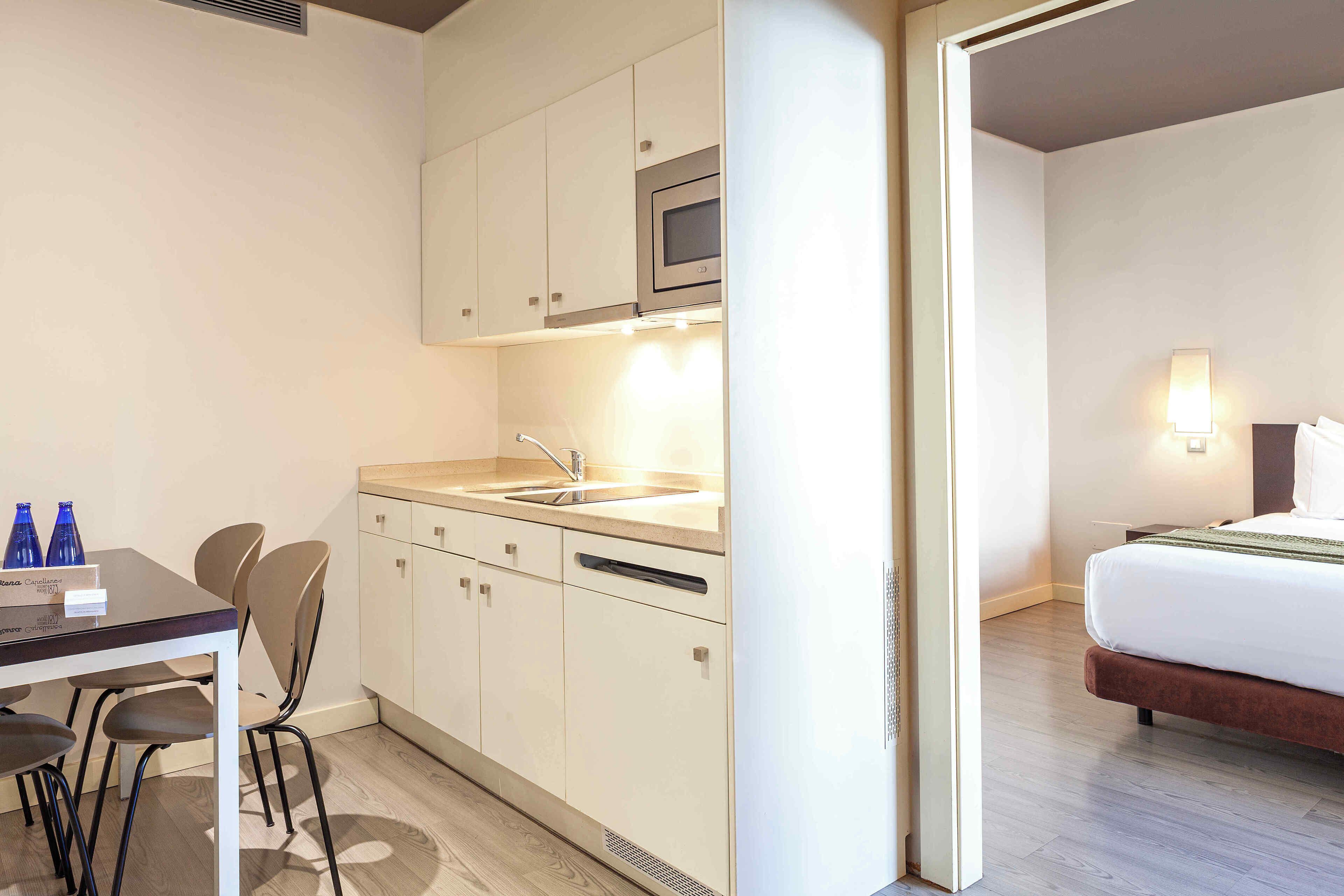 Una habitación de hotel compacta con kitchenette, una cama y baño.
