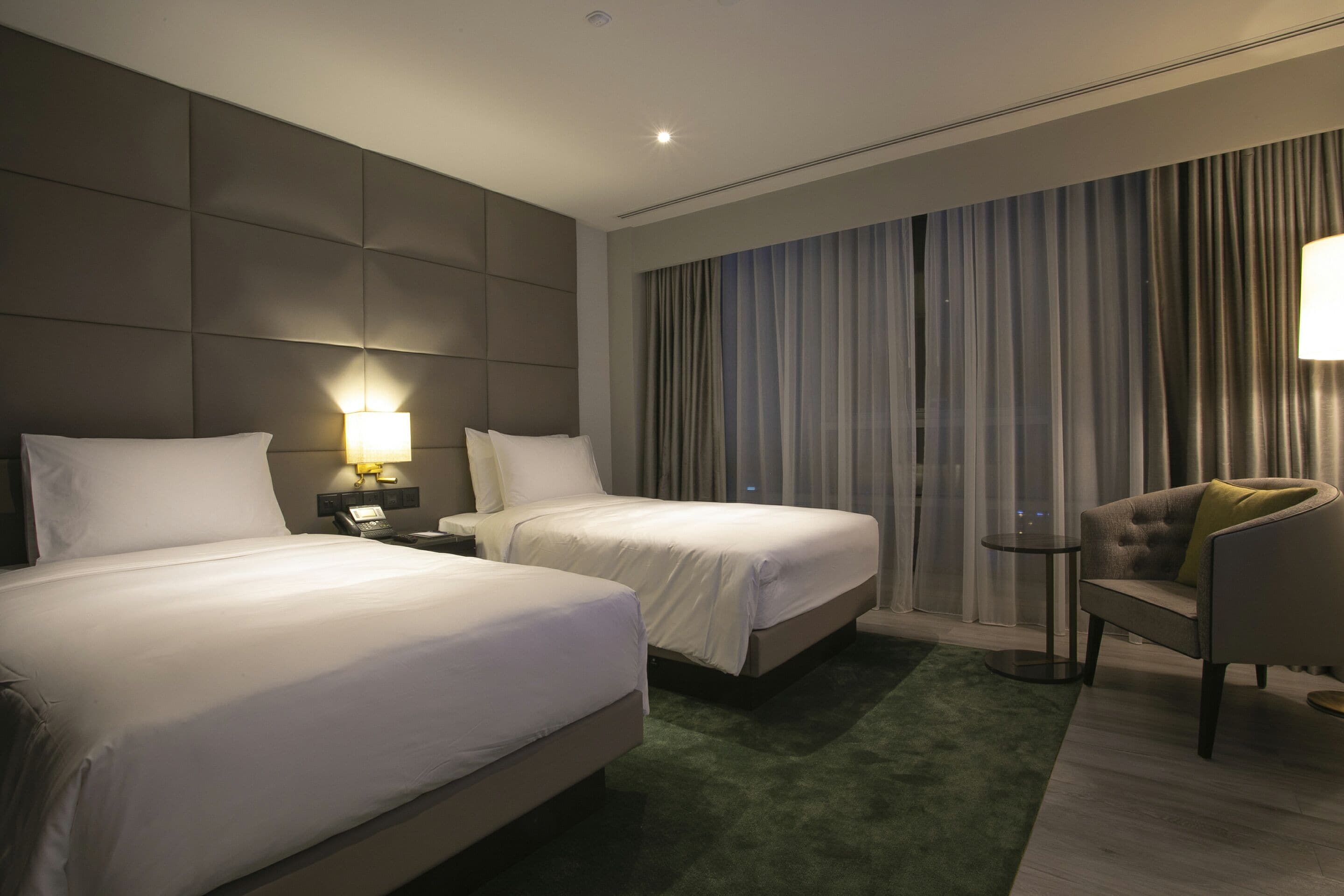 Habitación de hotel con dos camas, un sofá, una mesita y una lámpara.