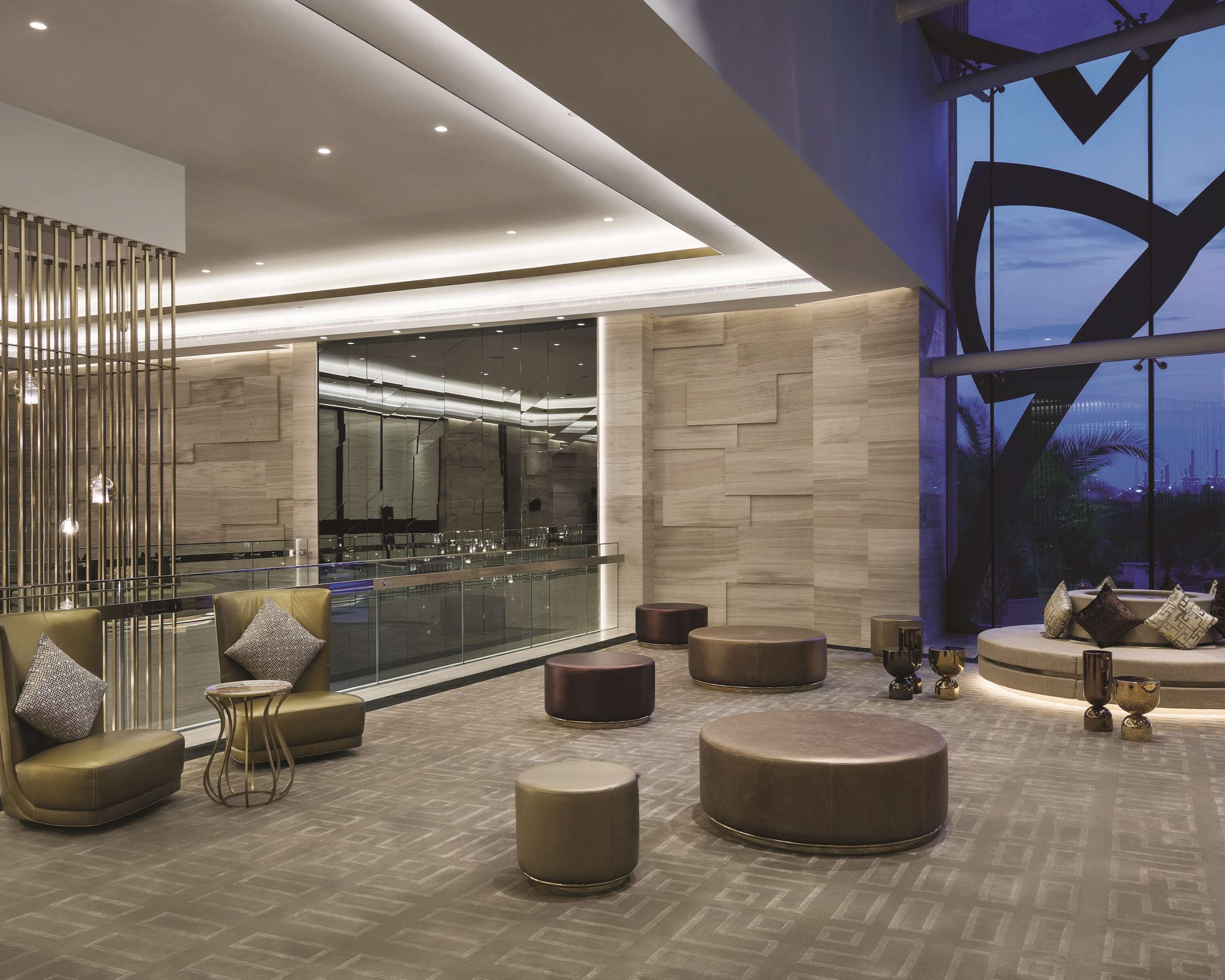 A modern lobby with a glass railing, seating areas, and a view of the cityscape.