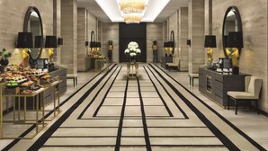 A spacious hotel lobby with a central chandelier, mirrored walls, and a long reception desk with a buffet. - Hyatt Regency Al Kout Mall (Fahaheel)