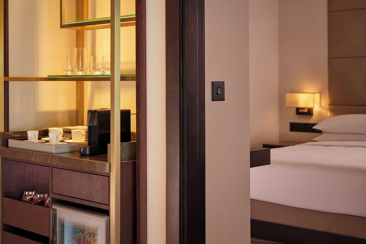 Una habitación de hotel con cama, mesita de noche y minibar.
