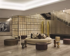 Relax in the stylish seating area with plush sofas and stools, surrounded by abstract art and elegant decor.