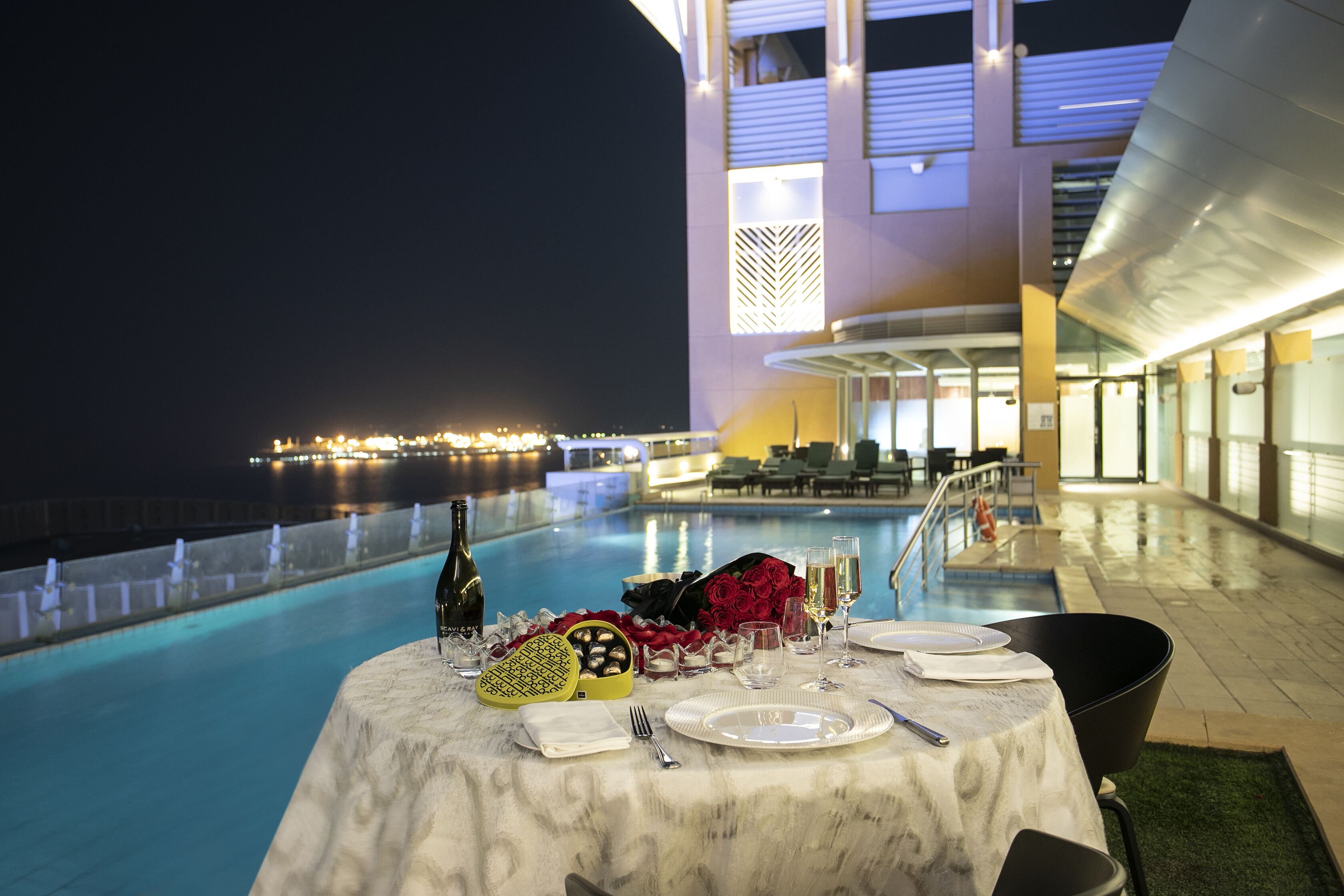 A table set for two with a view of a pool and a building in the background.
