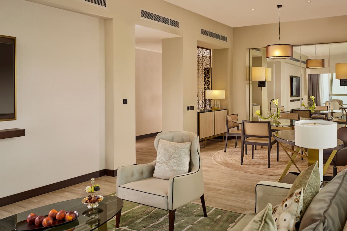Quarto de hotel moderno com área de estar, mesa de jantar e um espelho grande.