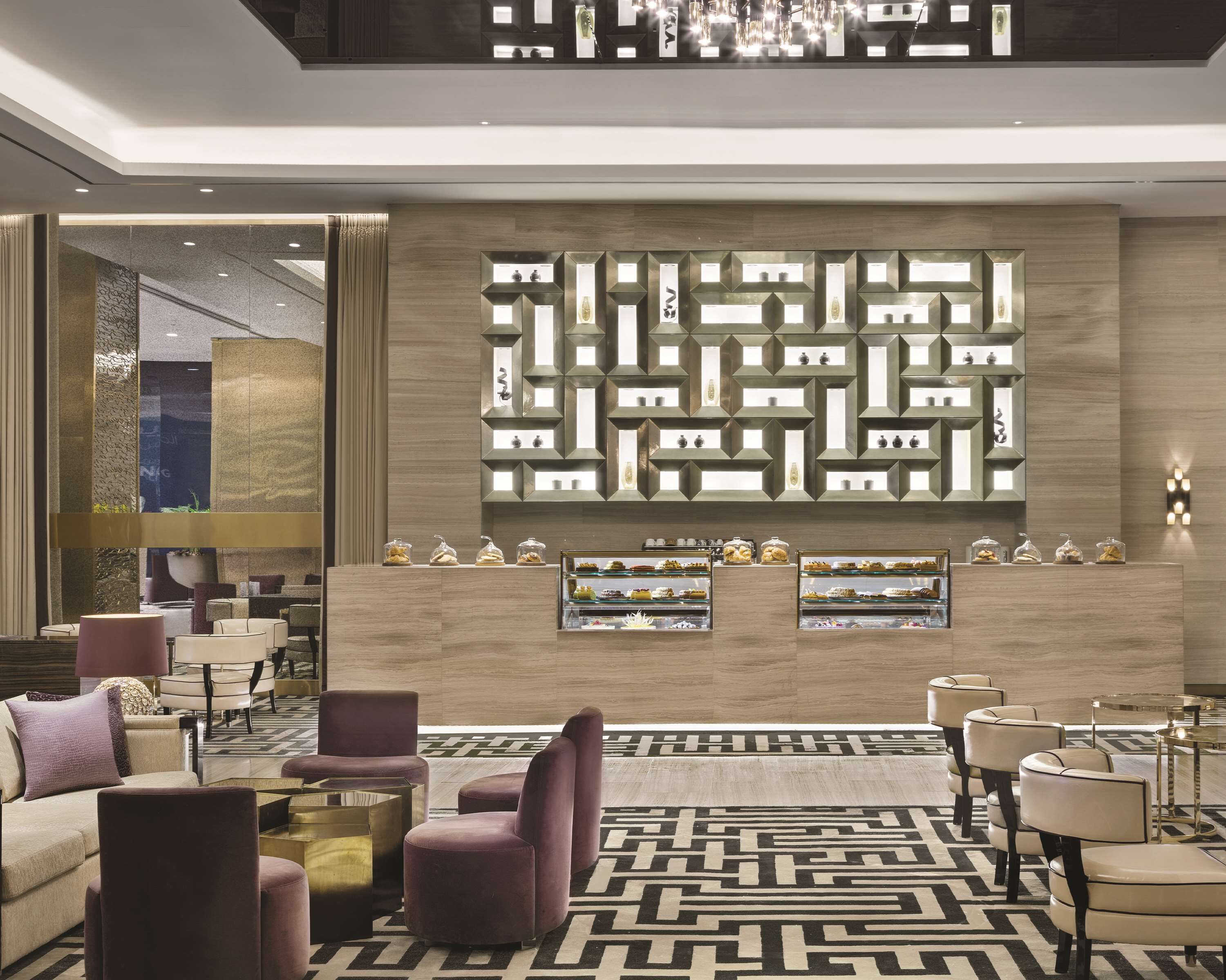 A modern lobby with a geometric wall design, seating area, and display cases with items.