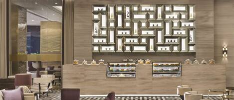 A modern lobby with a geometric wall design, seating area, and display cases with items.
