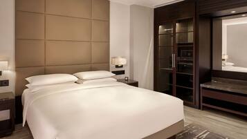 A hotel room with a large bed, a wardrobe, a mirror, and a nightstand with a lamp.