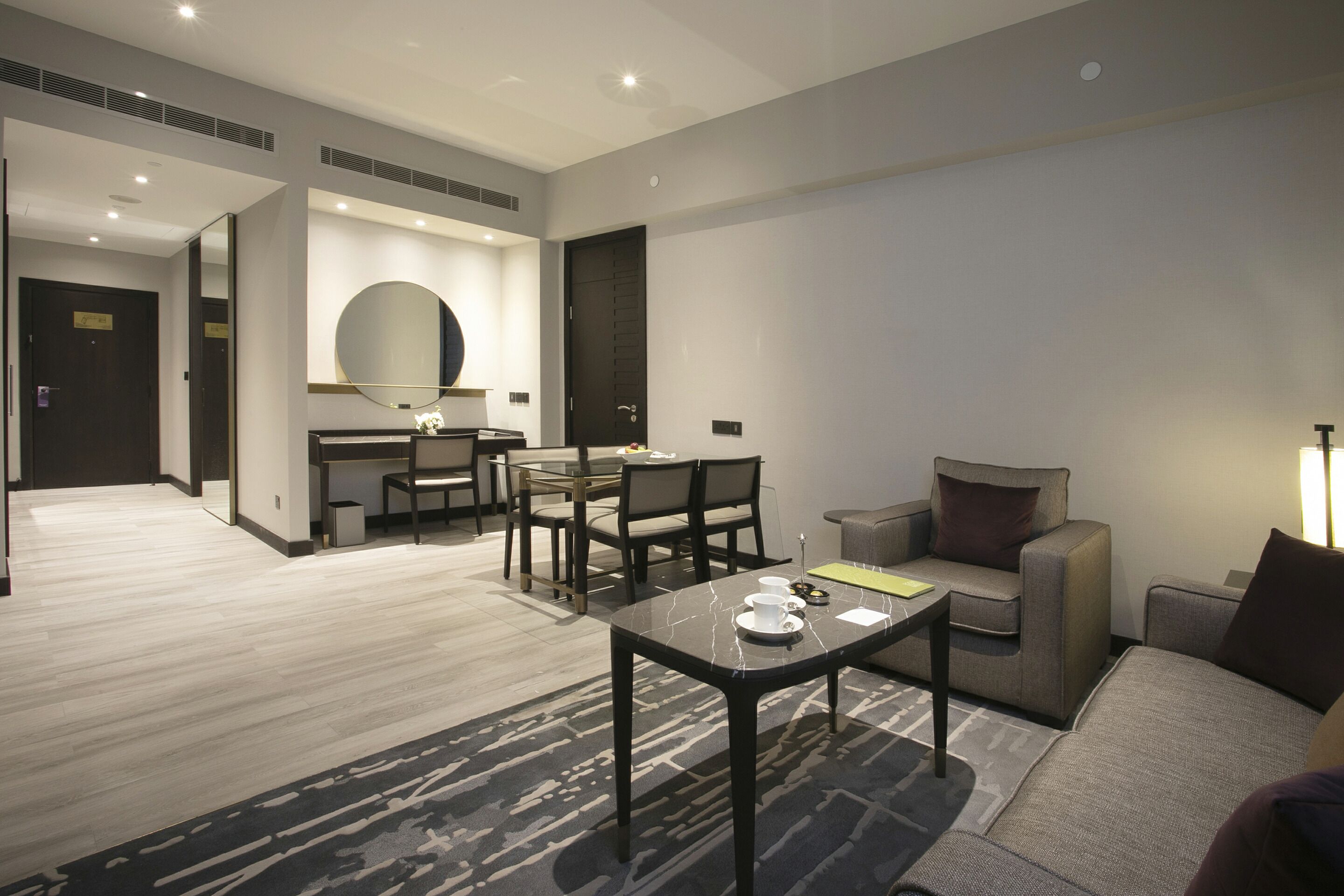 A modern hotel room with a dining area, a sofa, and a coffee table.