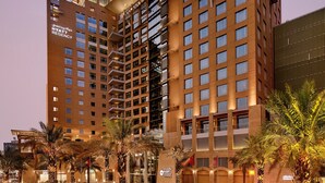 A multi-story hotel with a modern architectural design, featuring balconies and a well-lit facade. - Hyatt Regency Al Kout Mall (Fahaheel)