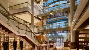 A spacious lobby with a central seating area, multiple staircases, and a large glass facade. - Hyatt Regency Al Kout Mall (Fahaheel)