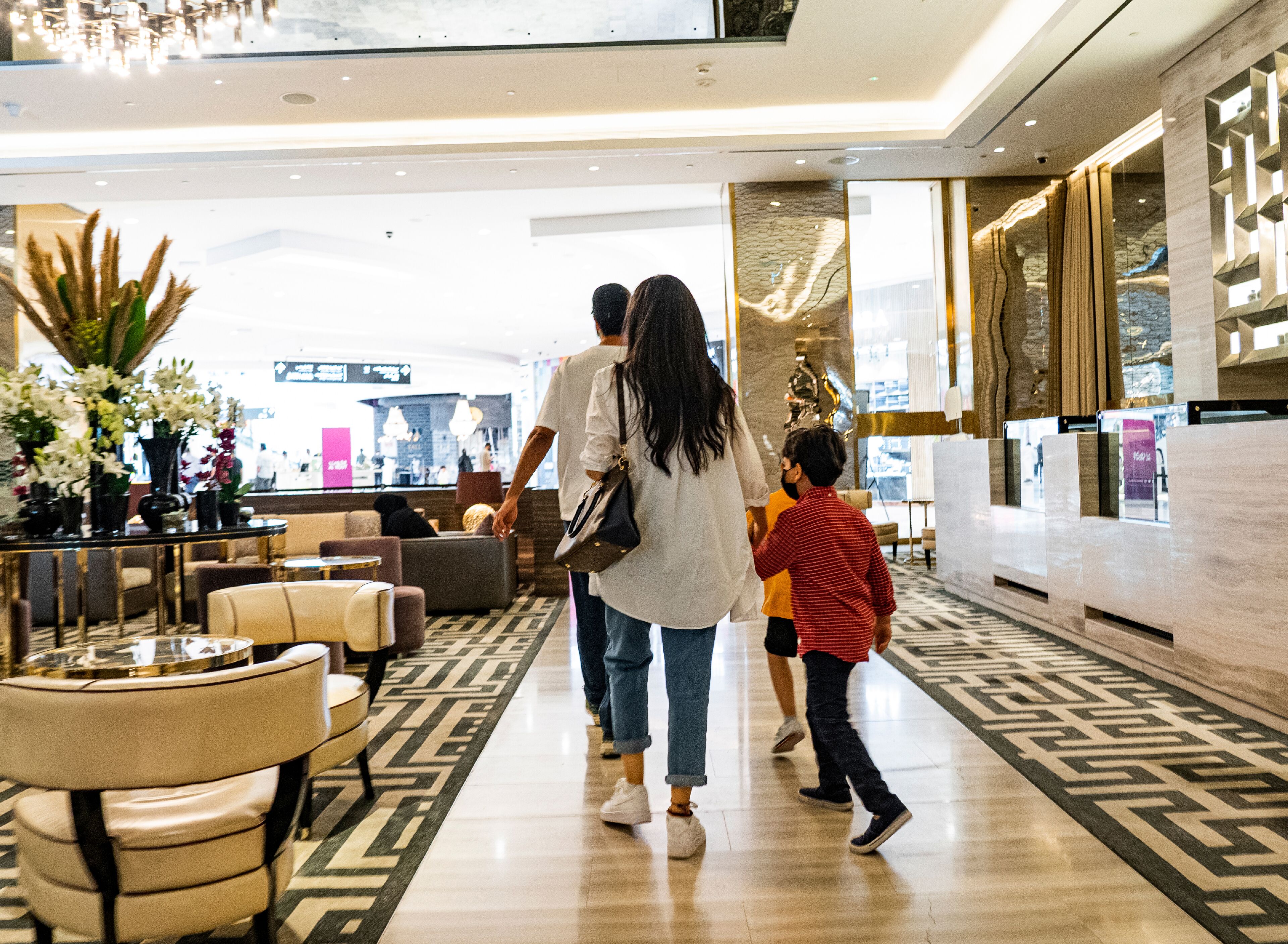 A hotel lobby with a modern design, featuring a patterned carpet, comfortable seating areas, and a reception desk.
