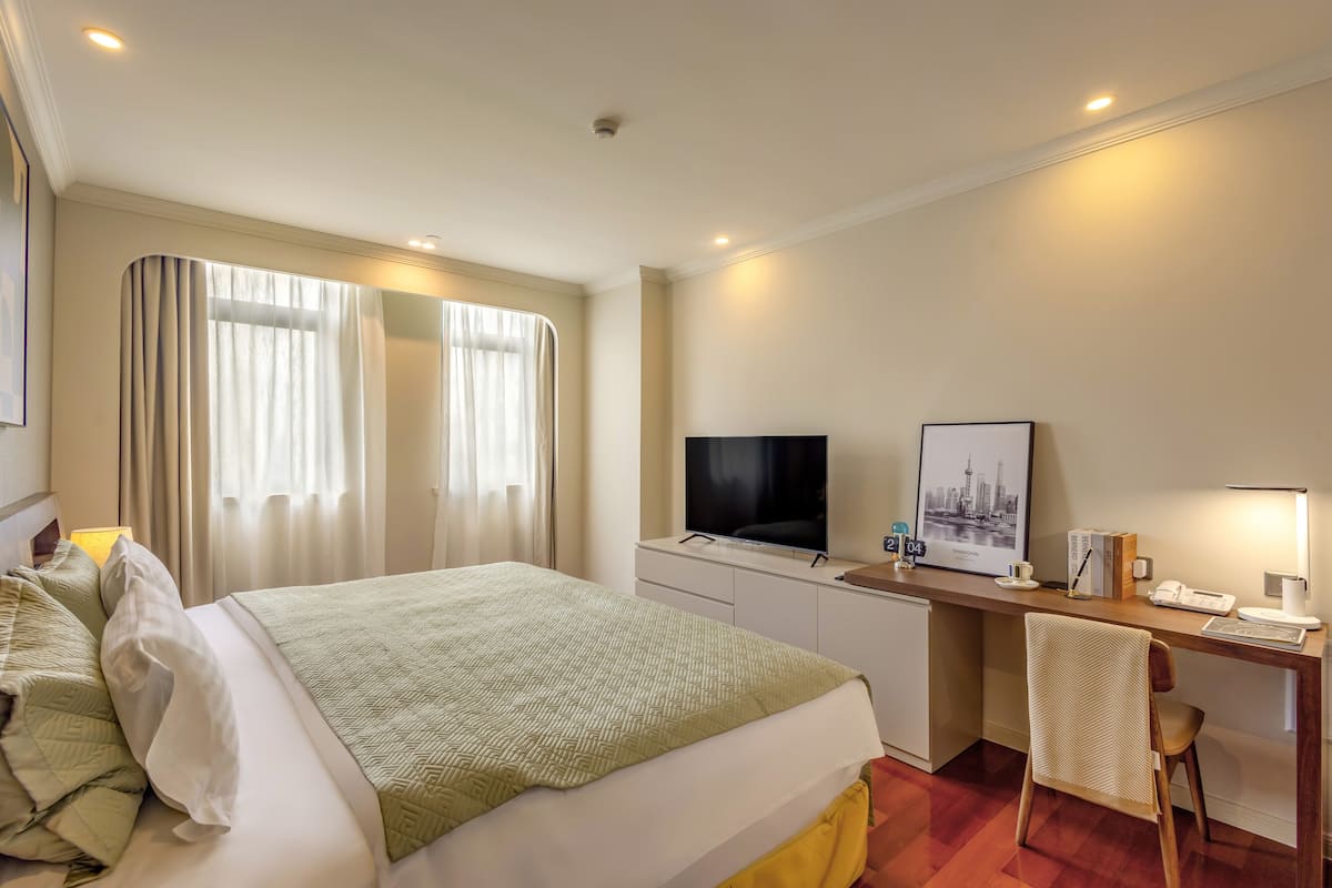 A hotel room with a bed, a desk, a television, and a chair.