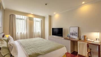 A hotel room with a bed, a desk, a television, and a chair.