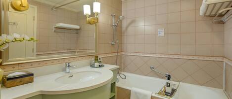 A bathroom with a large mirror, a sink, a bathtub, and a shower.