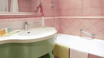 A bathroom with a sink, mirror, shower, and grab bar.