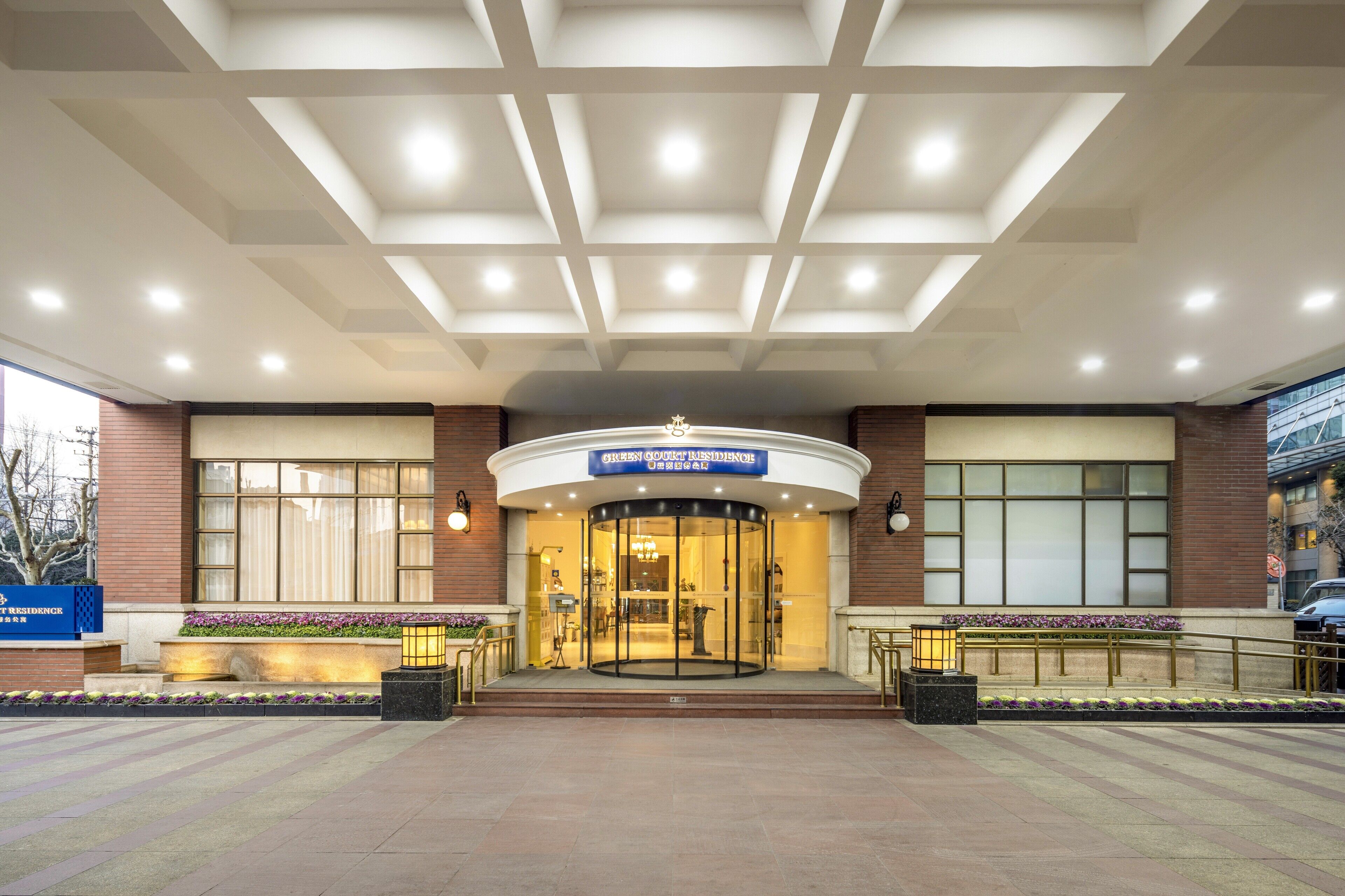 A hotel entrance with a glass revolving door, a blue sign above the door, and a brick facade.