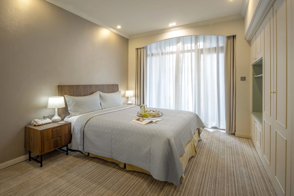 A neatly arranged hotel room with a large bed, bedside tables, and a wardrobe.