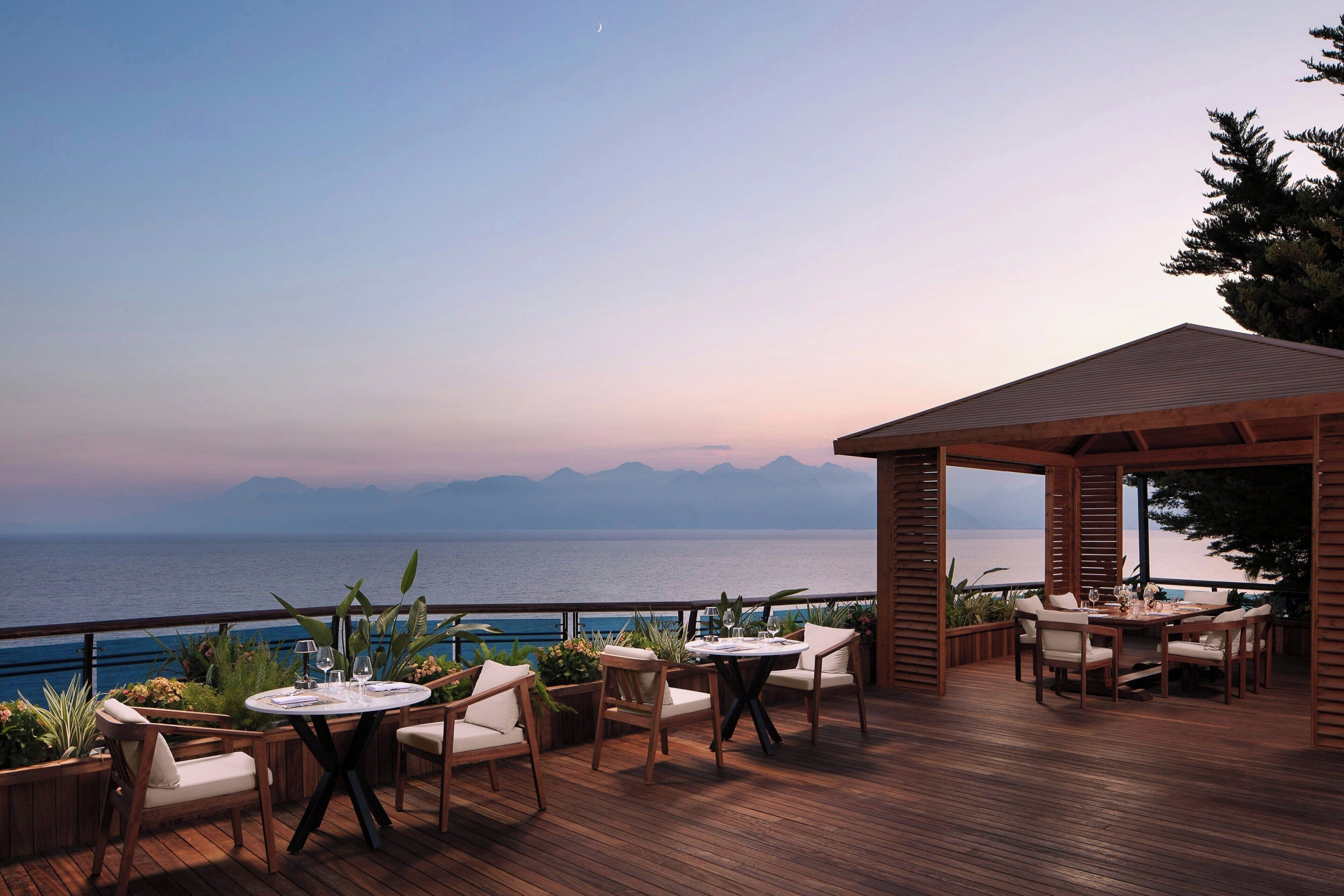 A wooden deck with outdoor seating and a view of the sea.