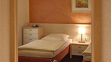 A hotel room with a bed, bedside tables, a lamp, a framed picture on the wall, and a mirror.