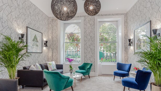 A modern living room with a sofa, two armchairs, a coffee table, and a potted plant. - Mentone Hotel (London)