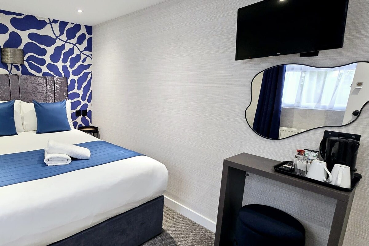 Une chambre d’hôtel comprenant un lit, une table de chevet avec une machine à café, un miroir et un téléviseur.