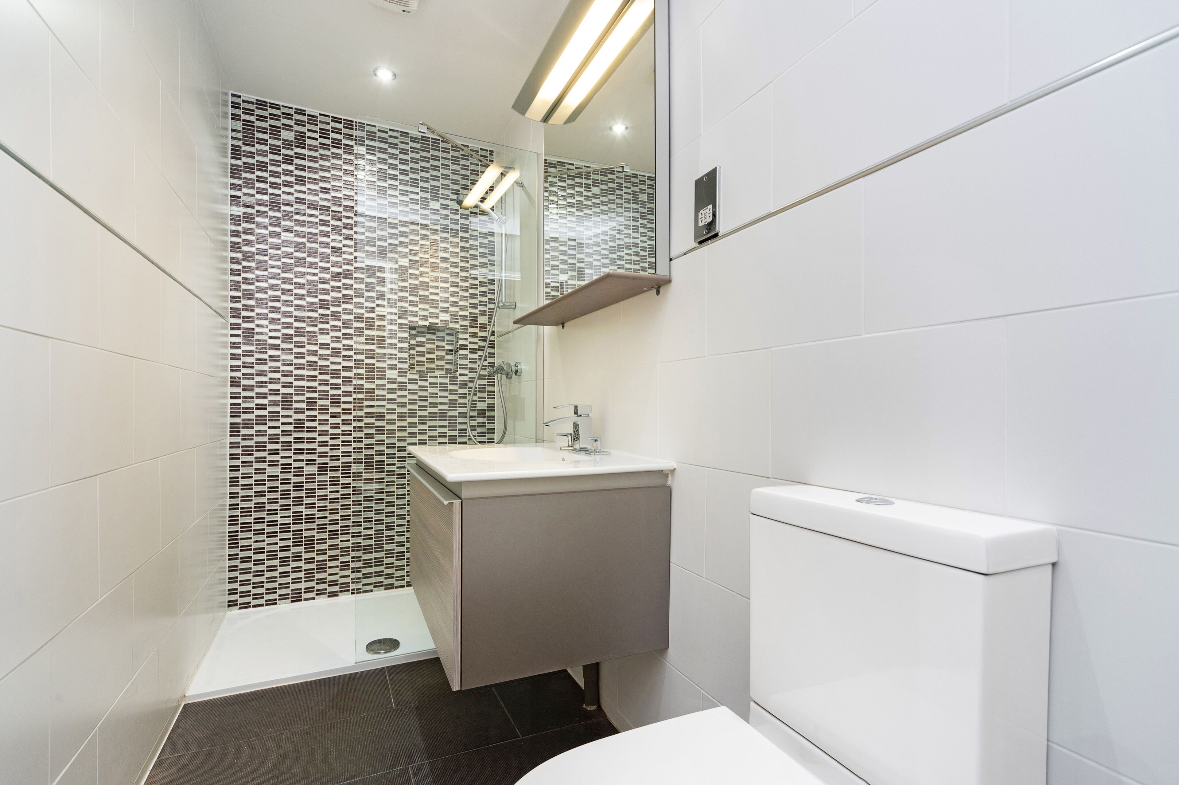 Et moderne badeværelse med bruser, vask og toilet.