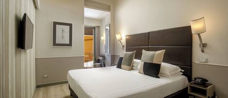 A hotel room with a large bed, bedside lamps, a telephone, and a framed picture on the wall.