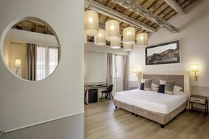 A hotel room with a large bed, a desk, a chair, a small table, and a mirror. - Condotti Palace (Rome)