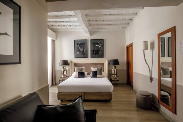 A modern hotel room with a large bed, bedside tables, a mirror, and artwork on the walls. - Condotti Palace (Rome)