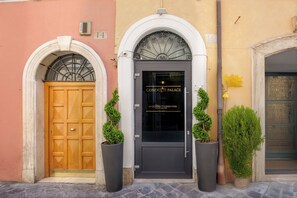 A building facade with a central entrance featuring a dark door with a sign reading "CONDOTTI PALACE". - Condotti Palace (Rome)