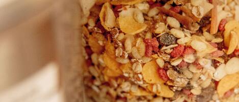 Primer plano de una mezcla de granola con diversos ingredientes como avena, nueces y frutas secas en un recipiente.