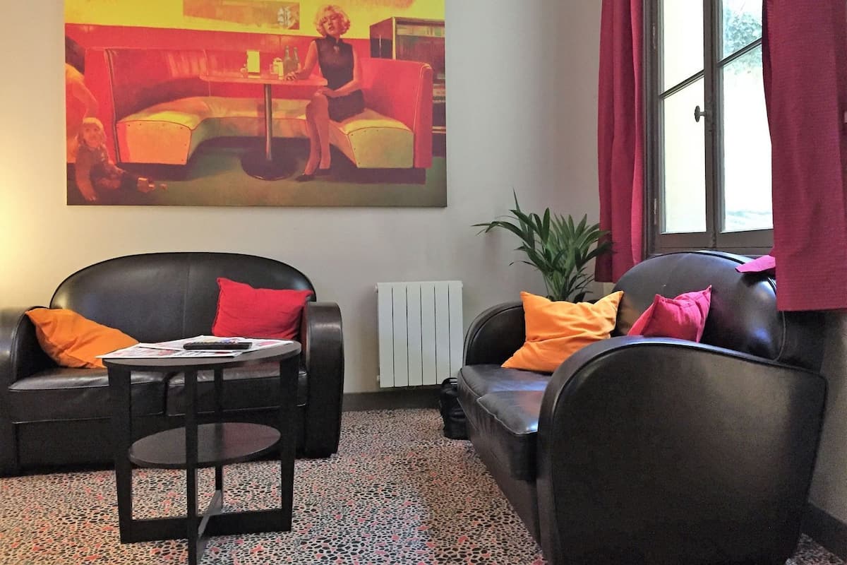 Una sala de estar con dos sofás de cuero negro, una mesita redonda y un cuadro abstracto grande en la pared.