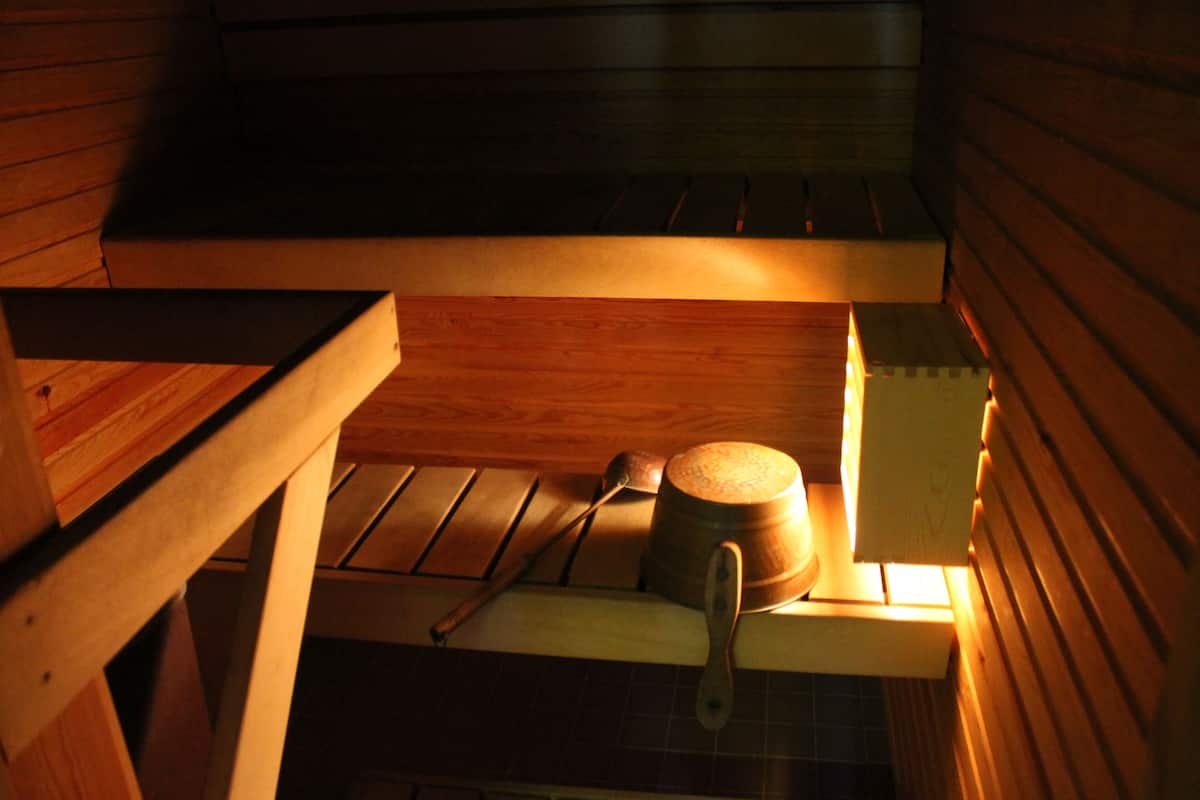 A wooden interior with a rustic kitchen area, including a wooden bench, a pot, and a spoon.