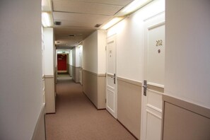 Corredor de hotel com portas numeradas 202, 203 e 204.
