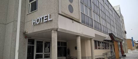 Un hotel con un llamativo letrero que dice 'HOTEL', grandes ventanales y una zona de acceso cubierta.