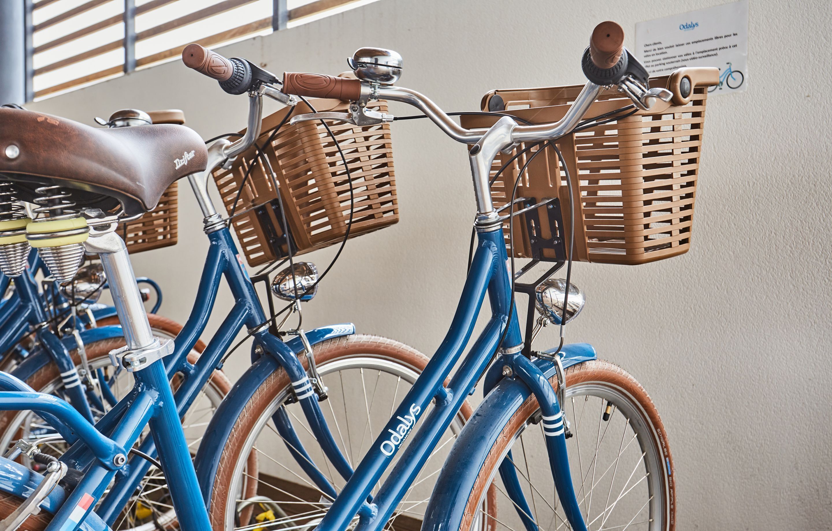 A row of blue bicycles with wicker baskets, parked indoors.