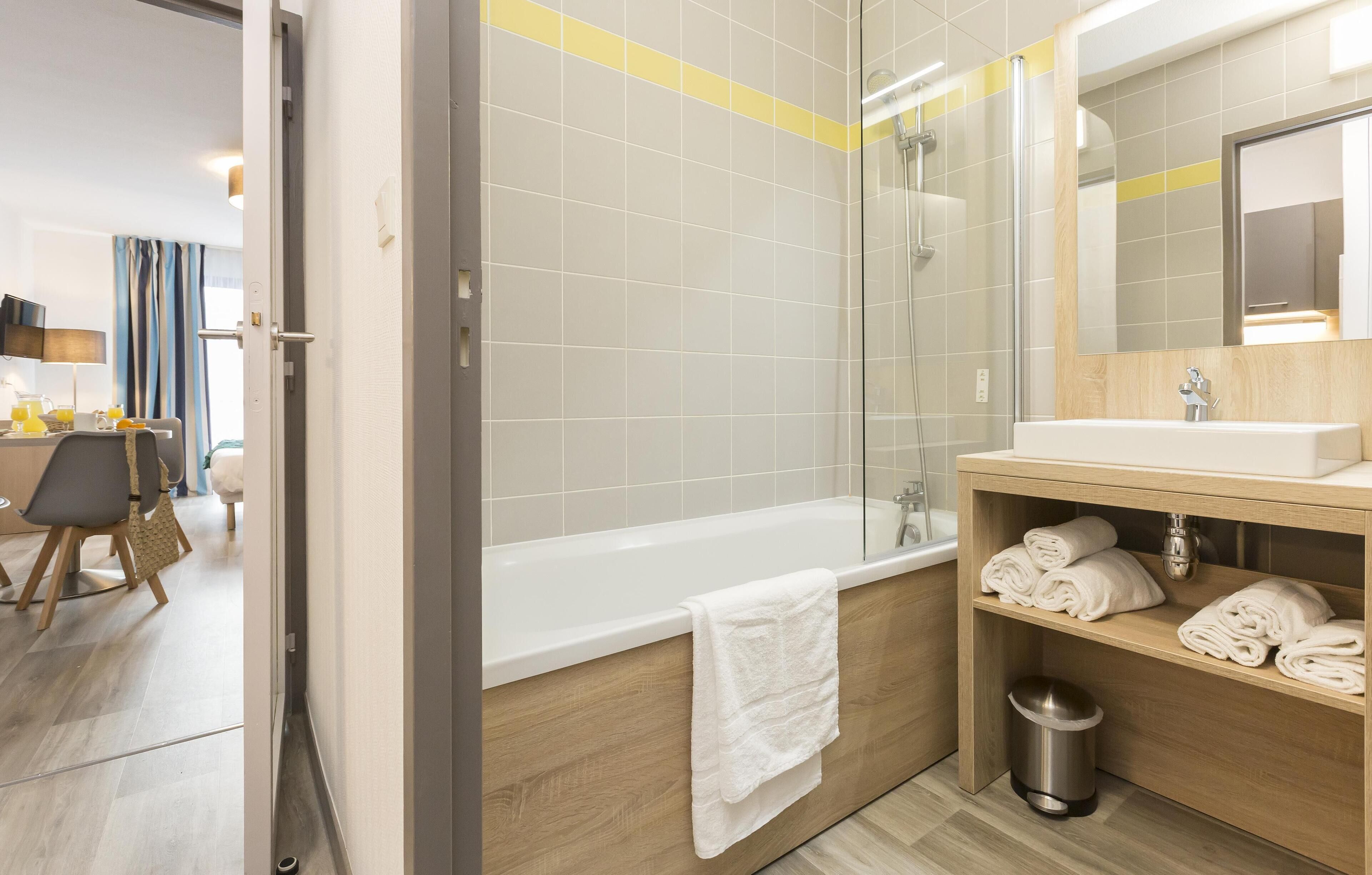 Een moderne badkamer met een bad, een douche en een wastafel met handdoeken.