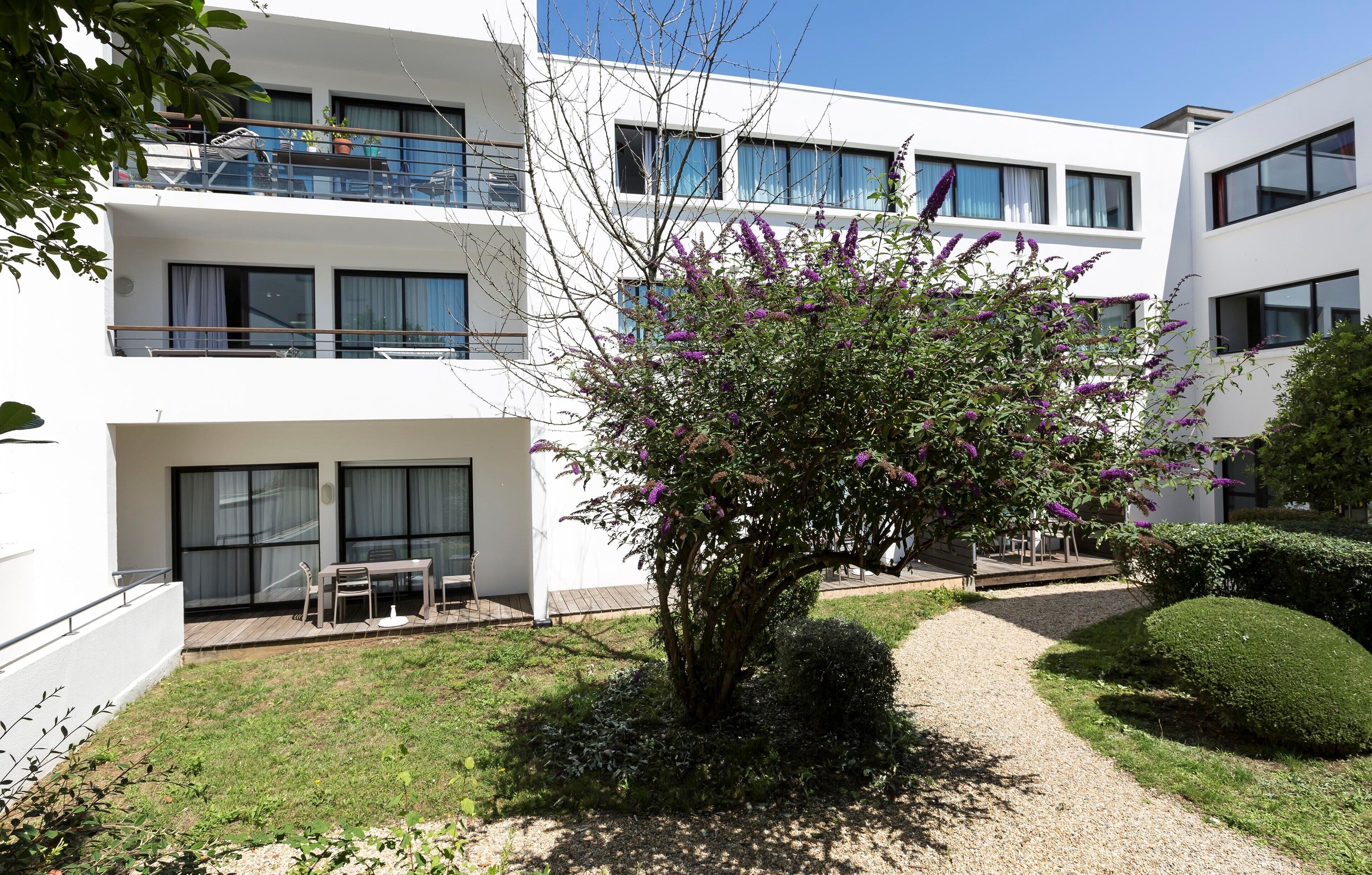 Un bâtiment moderne doté d’une cour intérieure, d’un petit jardin et d’un espace aménagé pour s’asseoir.