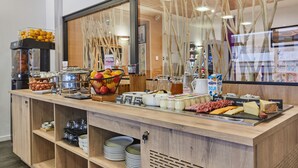 A buffet counter with various food items and beverages, including fruits, cheeses, and meats. - Résidence Hôtelière Odalys l'Archipel (La Rochelle)
