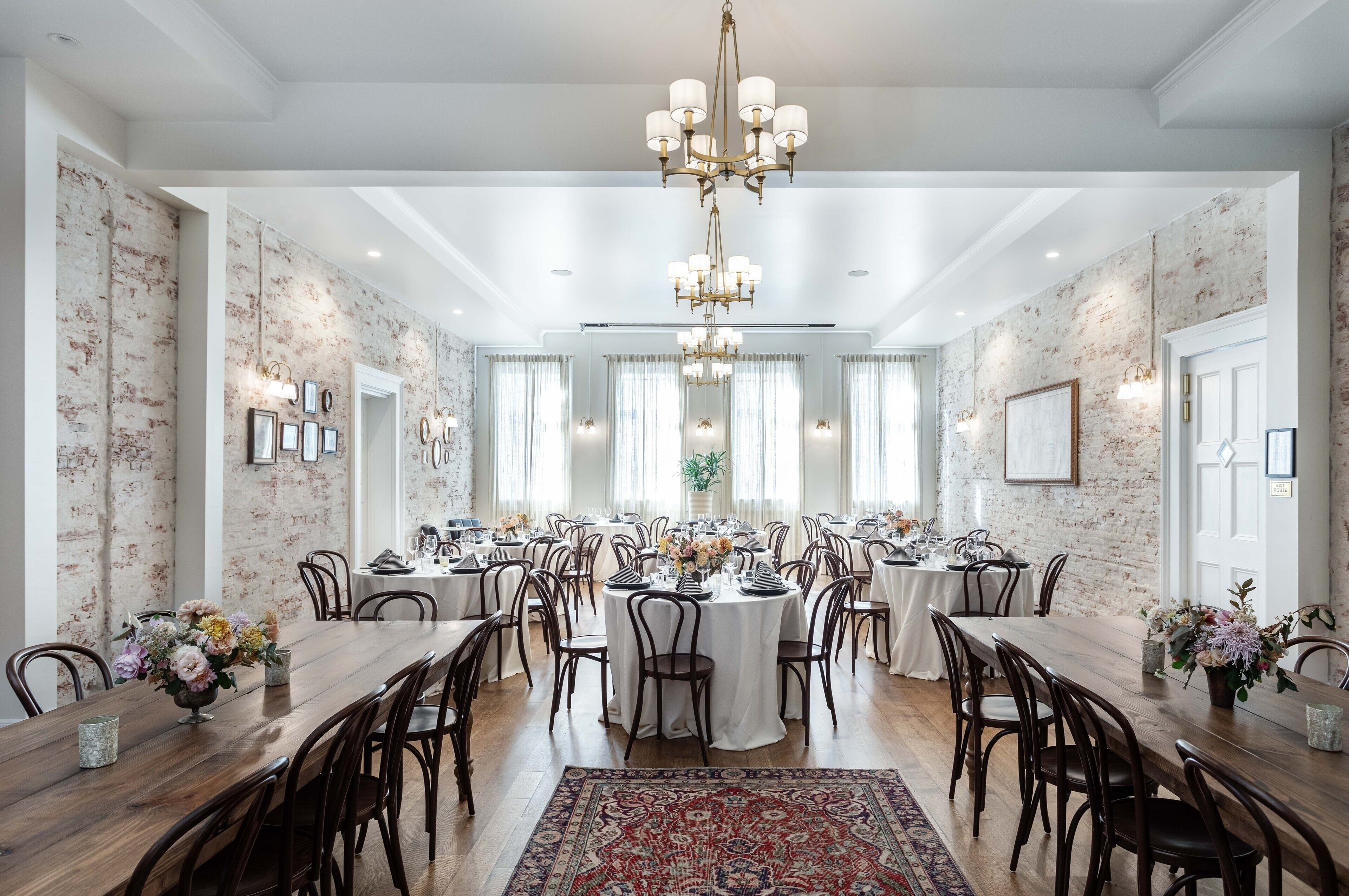 A spacious dining area with multiple round tables, dark wooden chairs, and a large chandelier.