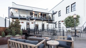 An outdoor seating area with wooden furniture and a fire feature. - Holbrooke Hotel (Grass Valley)