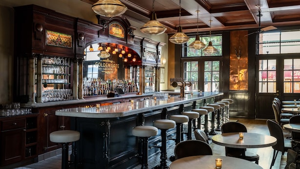 A bar area with a long counter, stools, and a variety of bottles and glasses. - Holbrooke Hotel (Grass Valley)