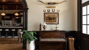 A bar area with a piano, a framed picture, and a plant. - Holbrooke Hotel (Grass Valley)
