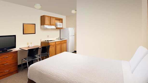 A hotel room with a bed, a desk with a computer, a television, and a microwave. - WoodSpring Suites Des Moines Pleasant Hill (Pleasant Hill)