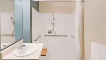 A modern bathroom with a white sink, mirror, and shower.