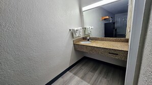 Un baño con lavamanos de encimera de granito, un espejo y un perchero para toallas.
