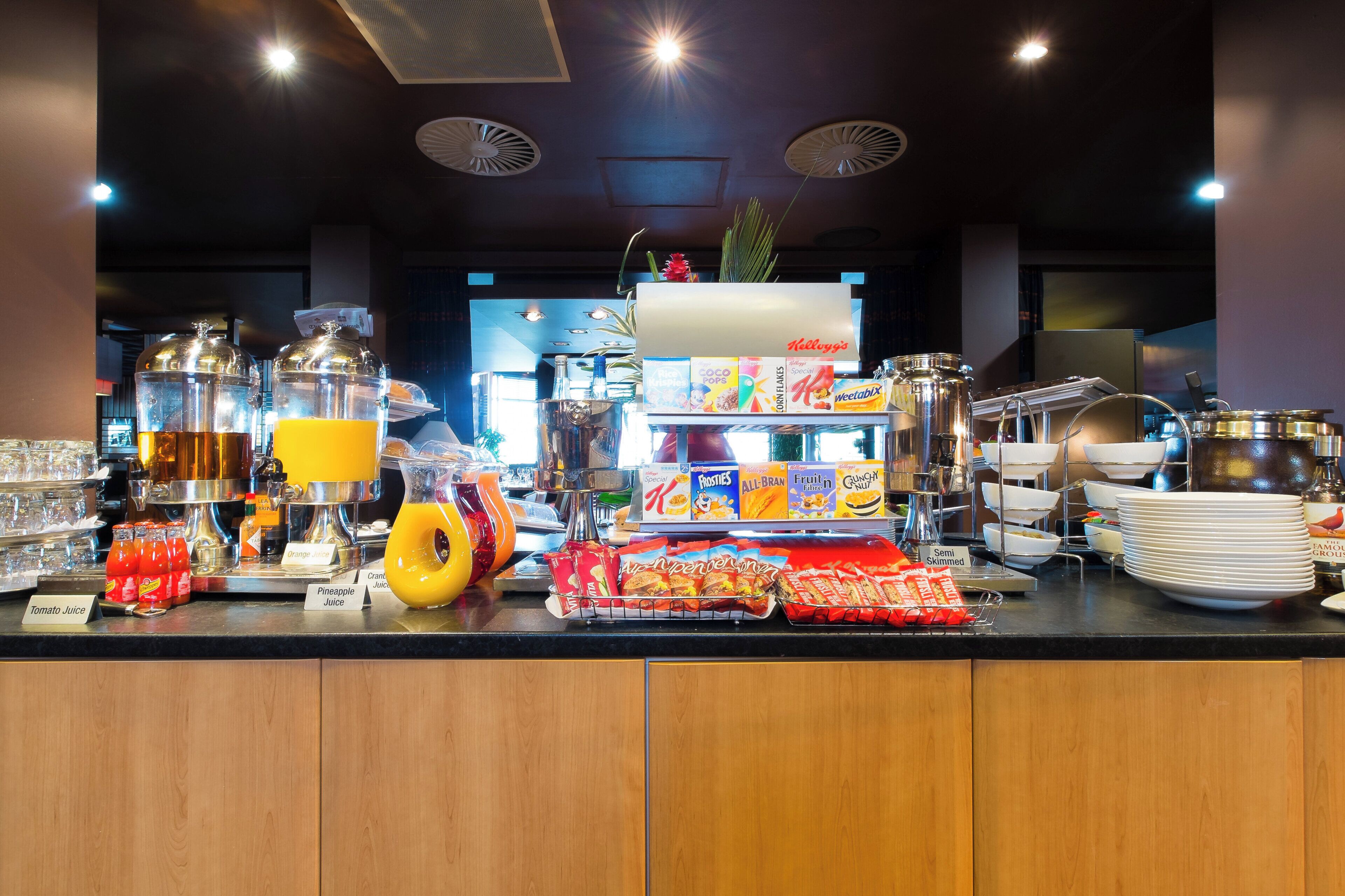 A buffet counter with various food items, beverages, and condiments.