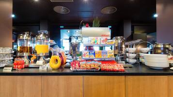 A buffet counter with various food items, beverages, and condiments.