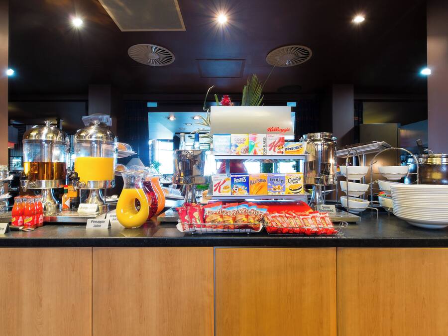 A buffet counter with various food items, beverages, and condiments.