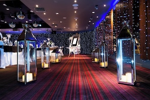 A hotel lobby with a red carpet, chandeliers, and decorative lanterns.